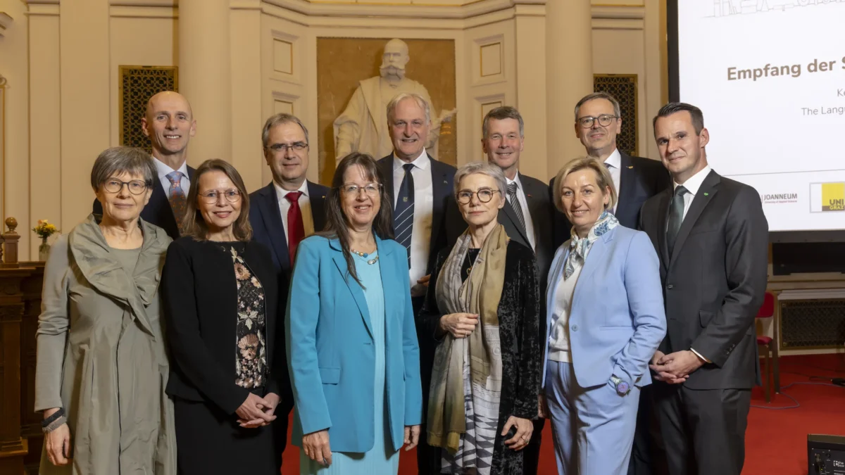 Foto auf 5min.at zeigt mehrere Personen in die Kamera lächeln.