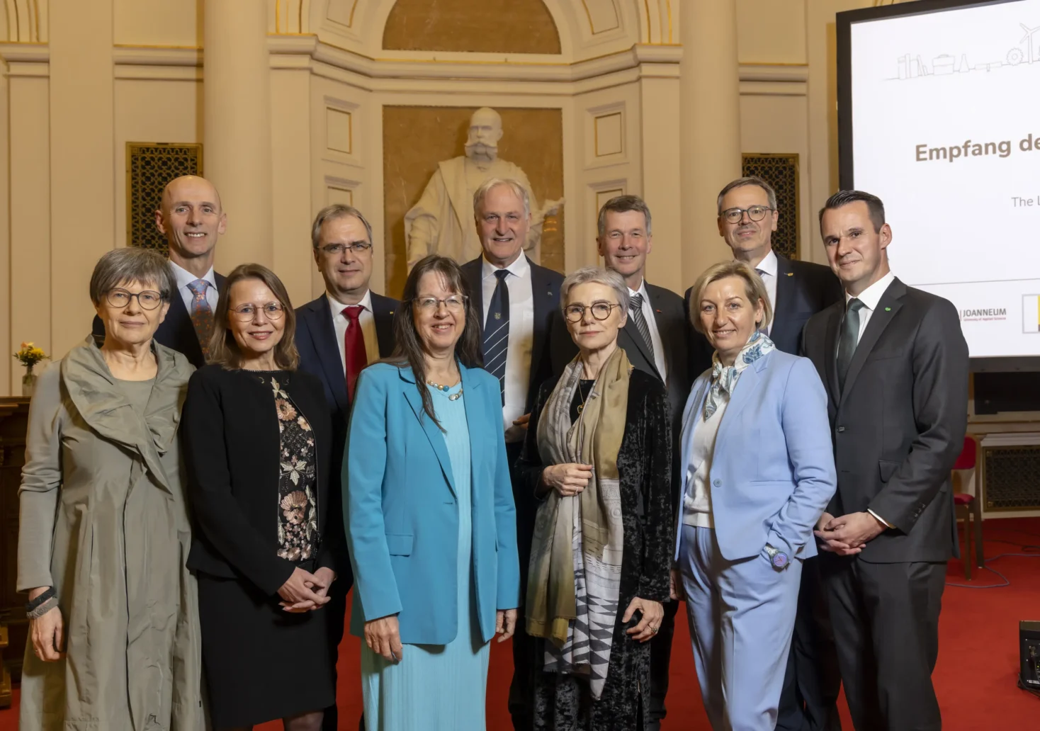 Foto auf 5min.at zeigt mehrere Personen in die Kamera lächeln.