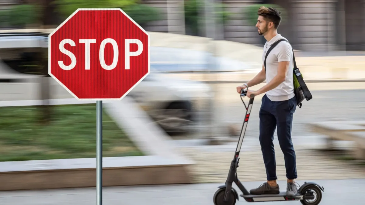 Auf dem Foto von www.5min.at sieht man einen E-Scooter Fahrer und eine Stop Tafel.