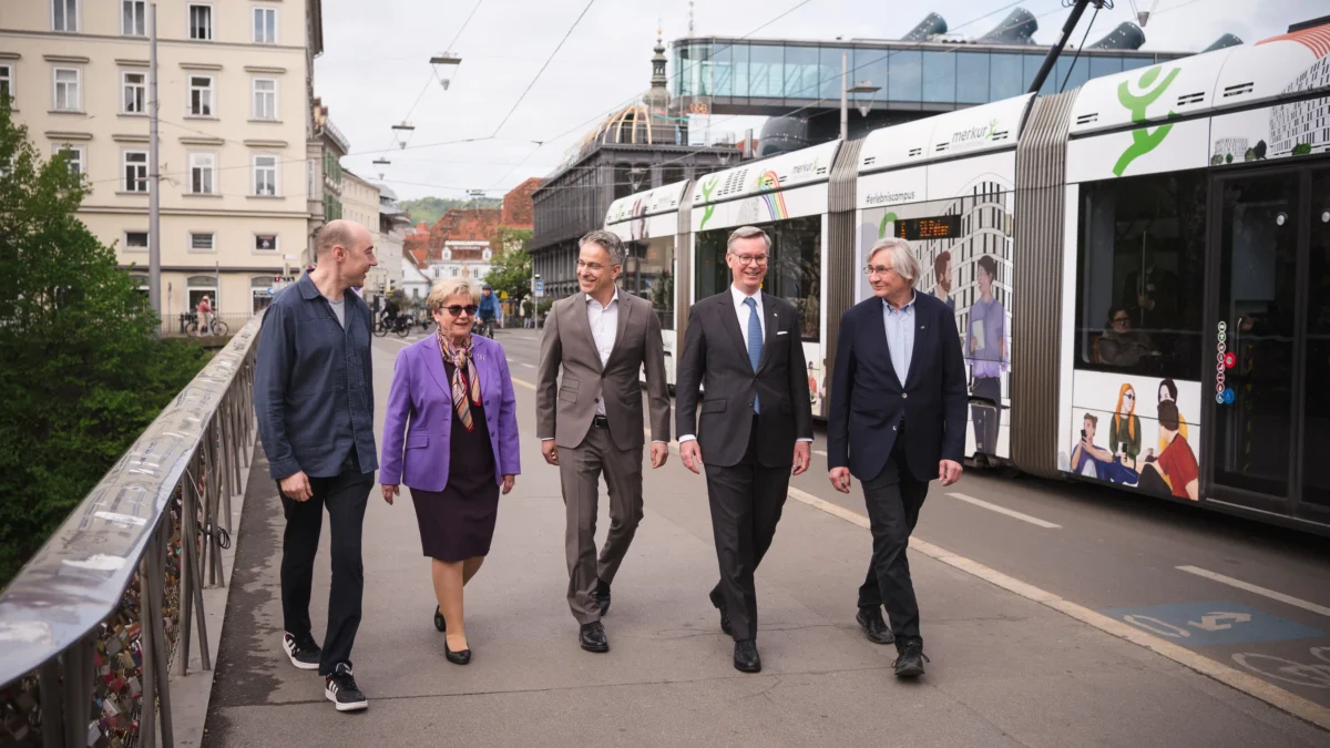 Foto auf 5min.at zeigt mehrere Personen in die Kamera lächeln.