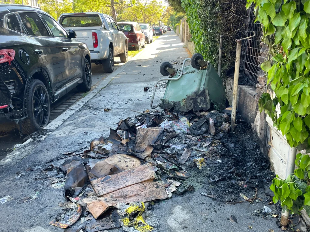 Foto in Beitrag von 5min.at zeigt die abgefackelte Mülltonne und viel Papier rundherum.